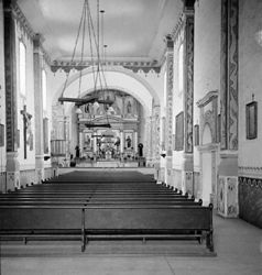 (PD) Photo: Keystone-Mast Company Inside the "cavernous" capilla (chapel) at Mission San Luís Rey de Francia, circa 1900. Dedicated in 1815, the cruciform design is shared only with the ruined "Great Stone Church" at Mission San Juan Capistrano, making the two structures unique among the Alta California missions in that regard.[2]