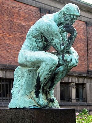 Statue of a man sitting, bending over in apparently deep thought.