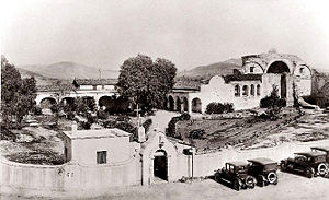 (PD) Photo: San Juan Capistrano Historical Society This 1921 view of the Mission San Juan Capistrano complex documents the restoration work that was already well underway by that time. The perimeter garden wall (including the ornate entranceway) and adjacent outbuilding are 1917 additions.