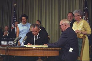 Lyndon Johnson signing Medicare bill, with Harry Truman, 30 July, 1965.jpg