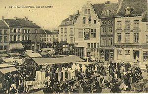 Picture from a postcard of a town square in France in 1900; buildings surround a square where there's a market.