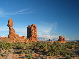 A giant rock about three stories tall, perched on another large rock; the large rock is balanced precariously jutting into the sky.