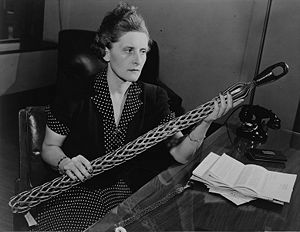 Picture of a woman holding a long cylindrical wiry cable, seated indoors