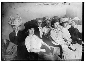 Picture of seven women wearing different dresses and hats with the words "First woman jury, Los Angeles" on the top of this black and white photo.