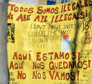 Picture of a large yellow sign saying "Todos somos illegales -- we are all illegals" caption reads Protest against the legal treatment of immigrants in Santa Cruz, California.