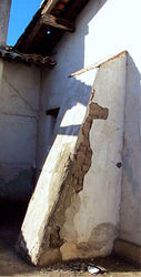 (CC) Photo: Robert A. Estremo An original exterior wall buttress at Mission San Miguel Arcángel, which suffered extensive earthquake damage on December 22, 2003. Sections of the plaster finish coat have sloughed off, exposing the adobes beneath to the elements.