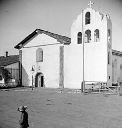 (PD) Photo: Keystone-Mast The capilla (chapel) of Mission Santa Inés as it appeared around 1900. The original bell structure (erected in 1817) collapsed in 1911 and was reconstructed out of reinforced concrete in 1948. The campanile has been compared by architectural historian Rexford Newcomb to the one that originally abutted the façade of Mission San Gabriel Arcángel.