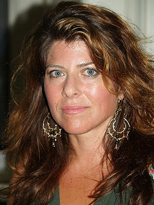 Picture of a woman with blue eyes and brown hair with large earrings.